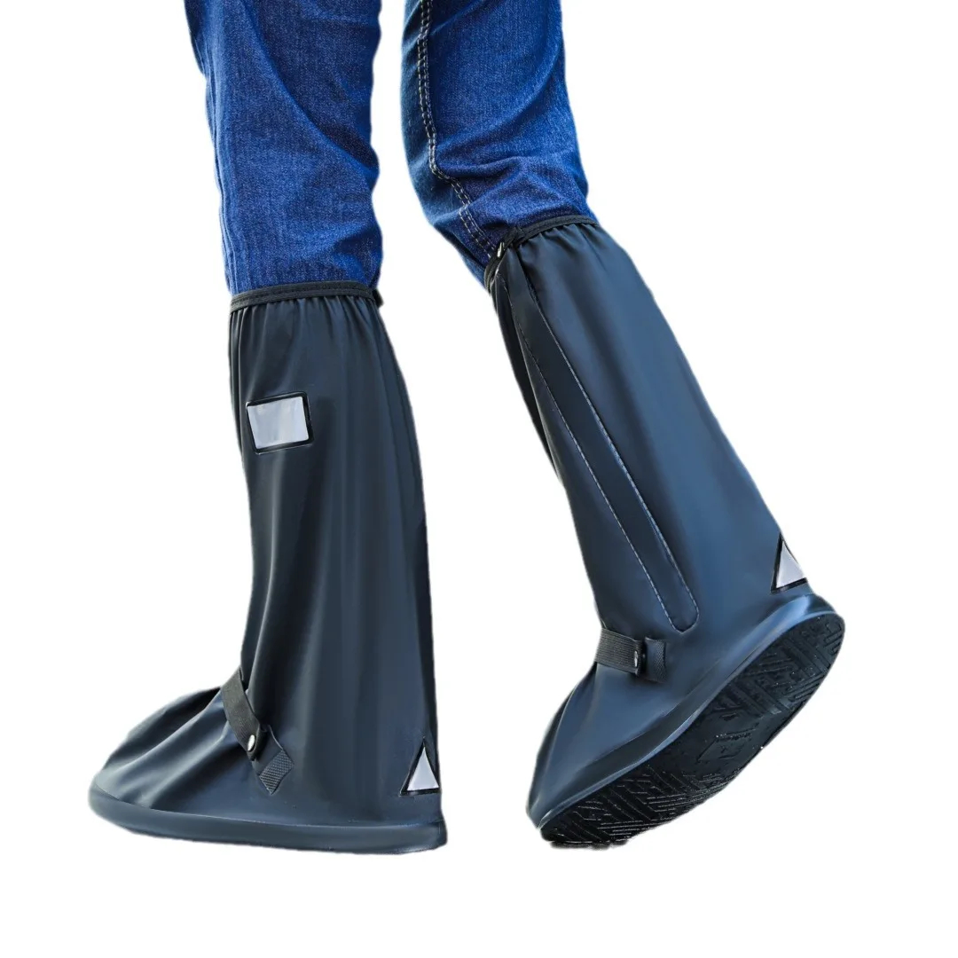 Pair of black high-tube waterproof shoe covers worn over jeans